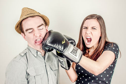 ein Mann und eine Frau. Die Frau hat Boxhandschuhe an und boxt den Mann ins Gesicht.