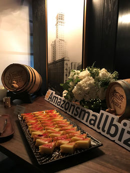 EIn Tisch mit kleinen Snacks sowie ein Schild auf dem #Amazonsmallbiz steht.